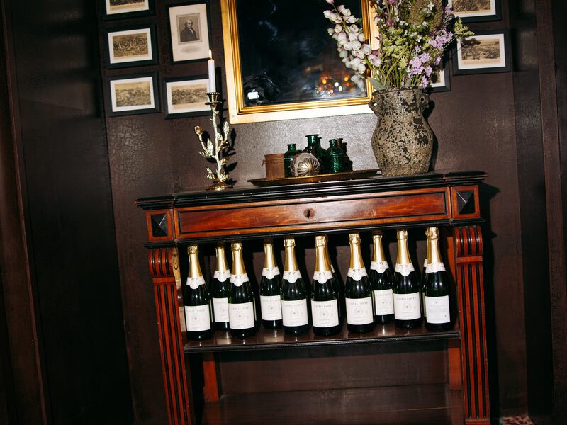 Champagne bottles beneath a gilded mirror on the antique sideboard