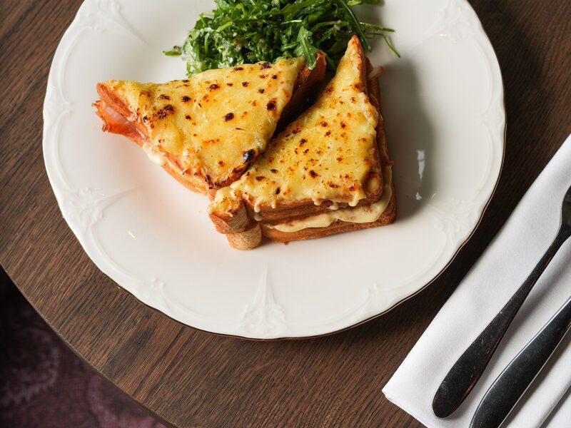 Croque monsieur with a fresh salad on white porcelain