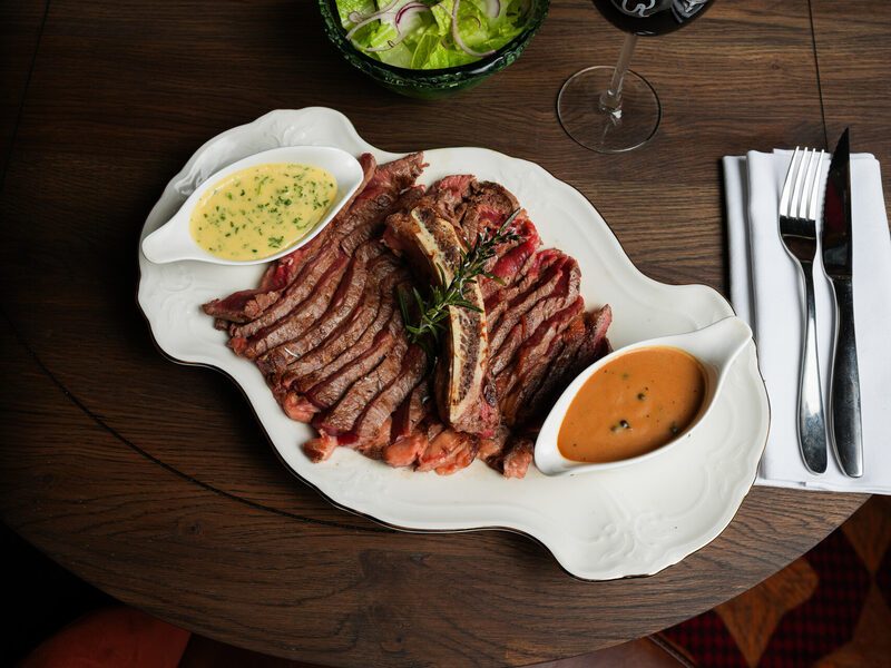 Sliced steak with two sauces, salad and a glass of red