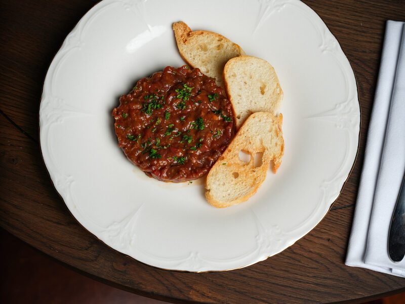Steak tartare with crostini on decorated porcelain