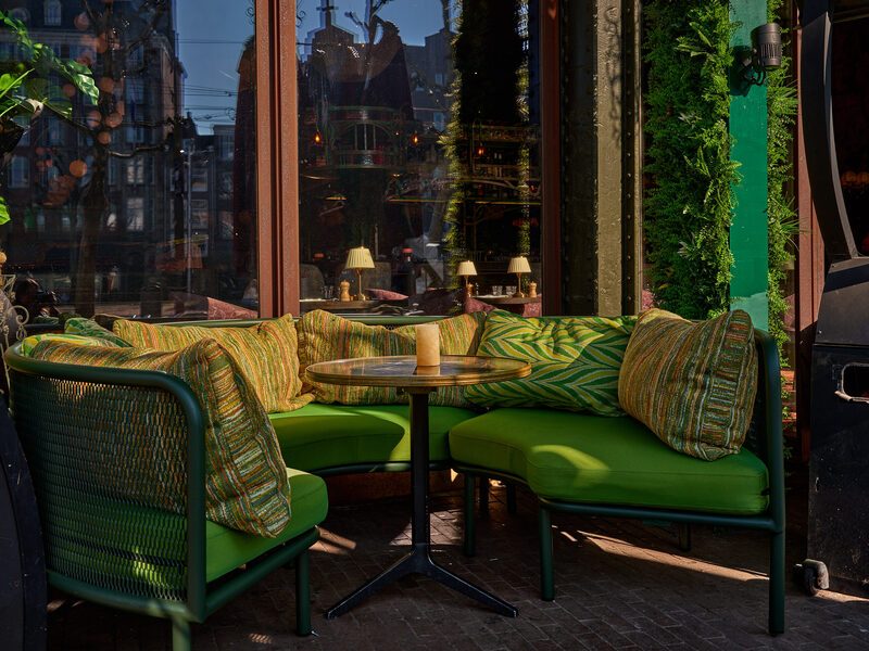 Green seating by the tall windows facing the square