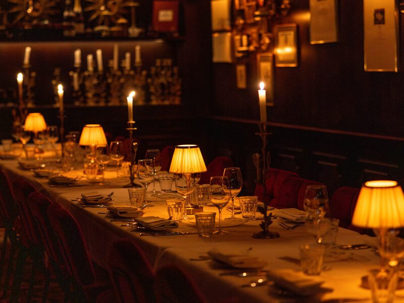 The Private Dining: a long set table with candles and brass lamps