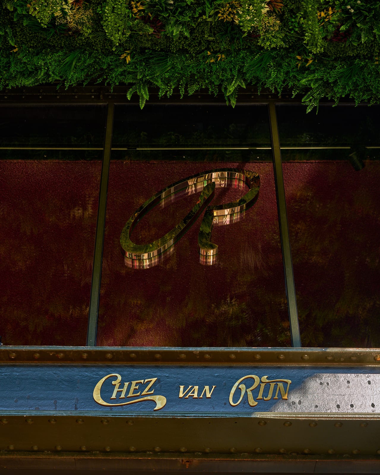 The Chez van Rijn facade: gold lettering on the steel balcony of the De Kroon building