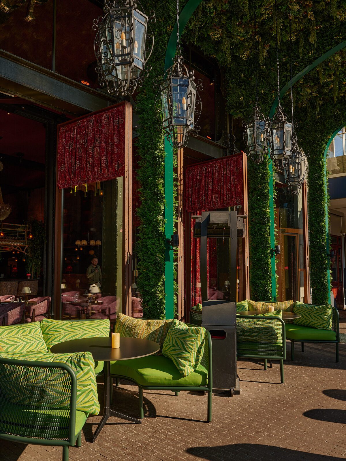 The Chez van Rijn terrace on Rembrandtplein with green lounge sofas and lanterns